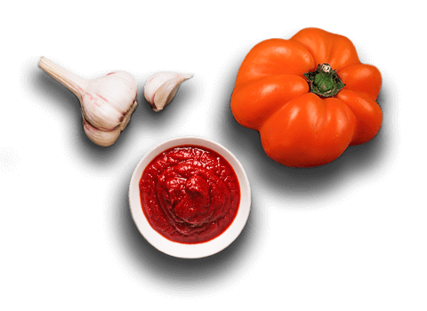 garlic and a tomato next to a pizza sauce - far away