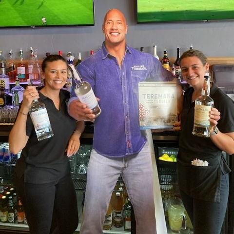 two women posing next to a dwayne johnson cut-out 